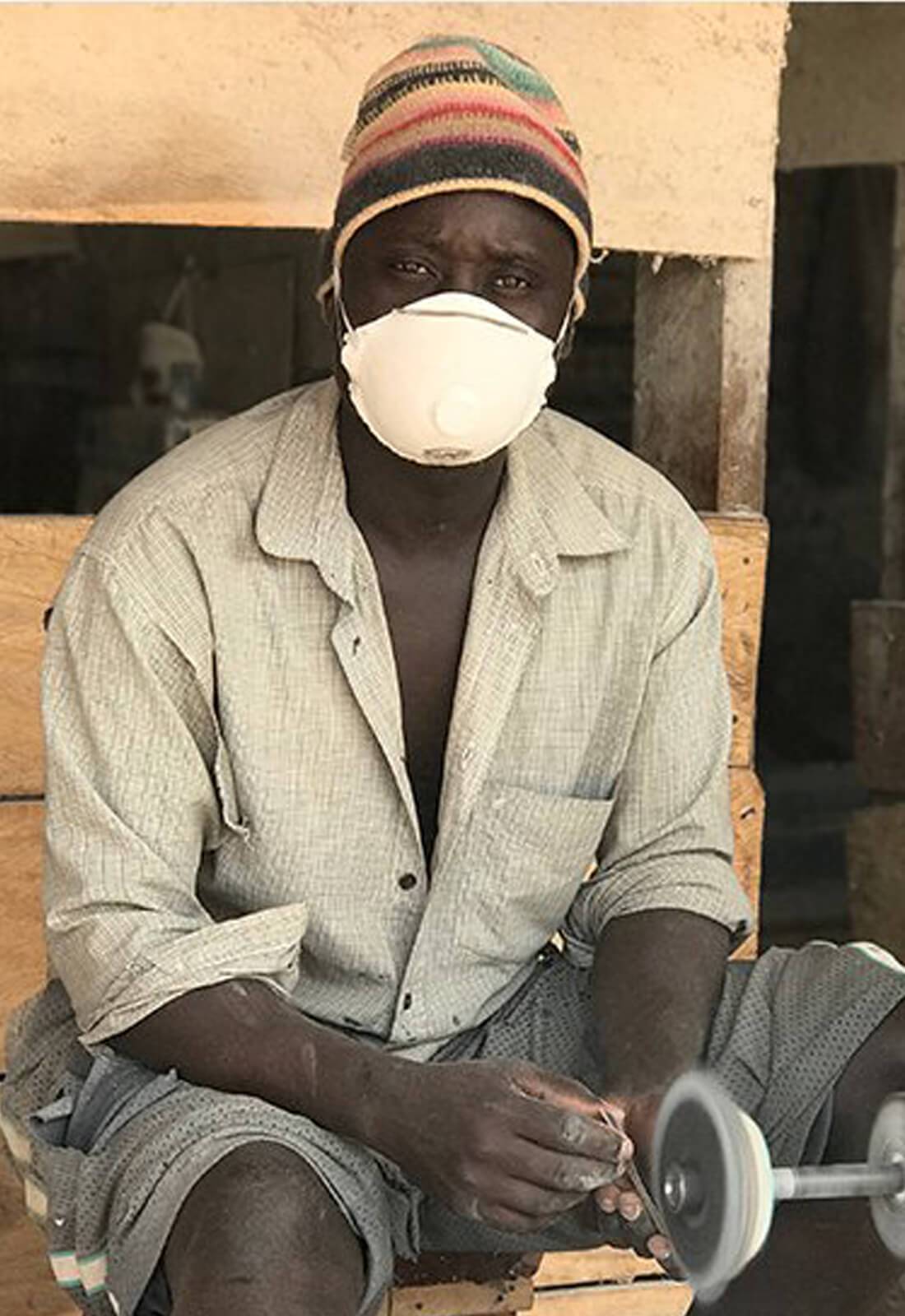 Ugandan cow horn artisan sitting at his workbench 