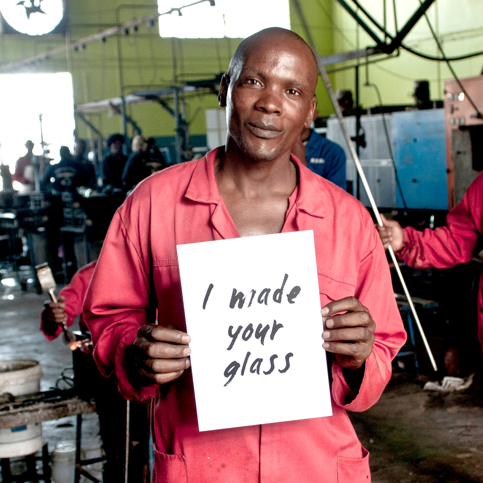 Ngwenya glass artisan holding a sign that reads "I made your glass"