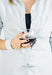 Off center red wine glass, held in a woman's hand 