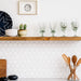 Open shelves in a kitchen, styled with olive green recycled glass wine glasses 