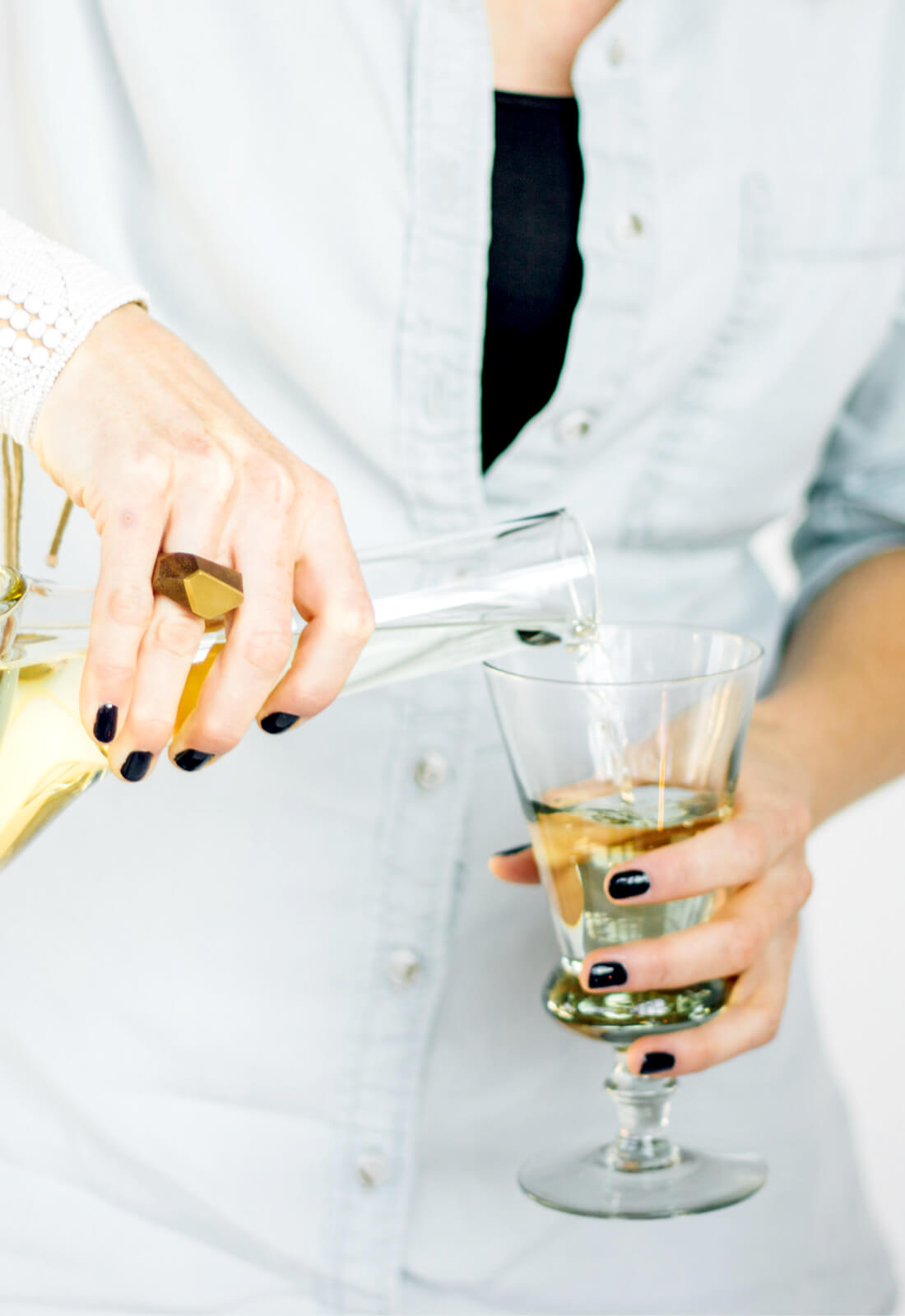 Woman pouring white wine into a thistle shaped wine glass 