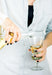 Woman pouring white wine into a thistle shaped wine glass 