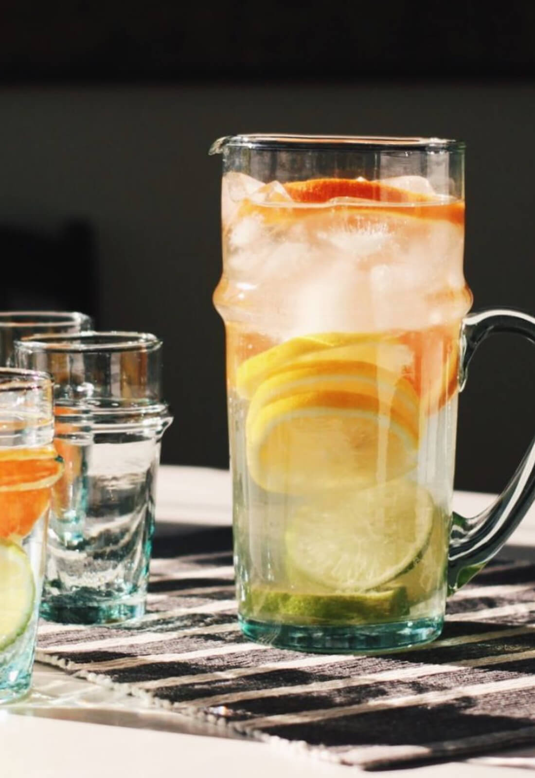 Curved glass jug with handle, shown with citrus water. Made in Morocco. 