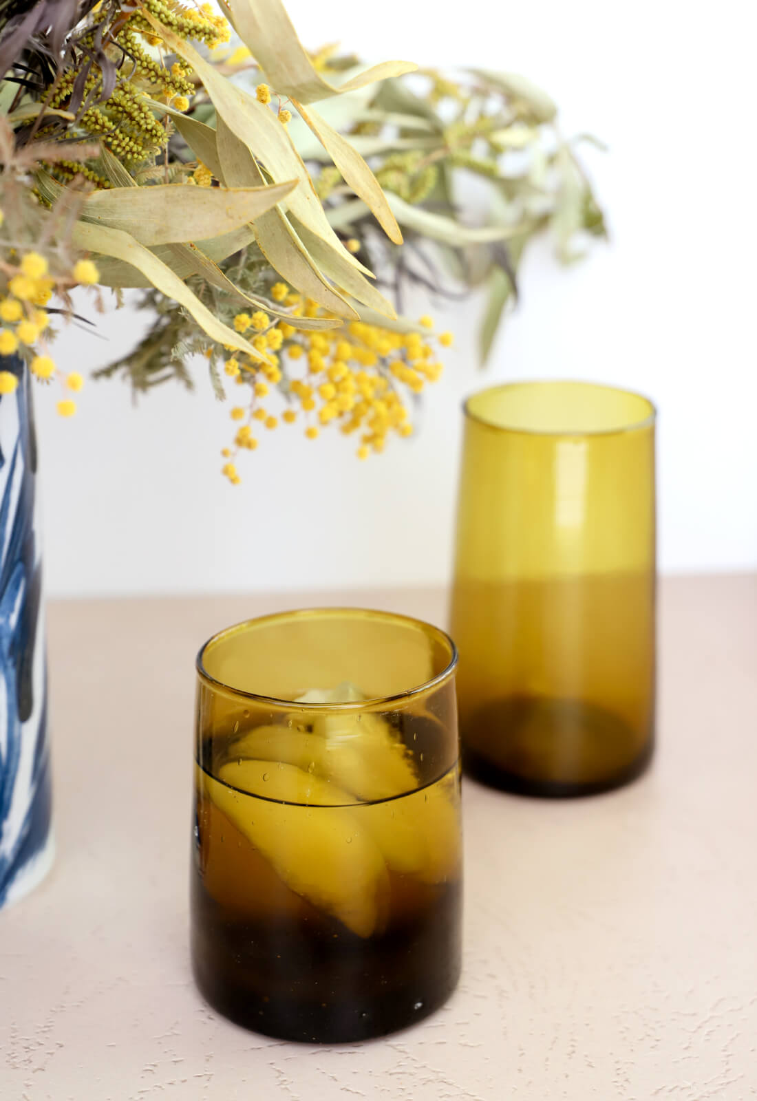 Amber brown tinted Moroccan recycled drinking glasses, styled on a dining room table 
