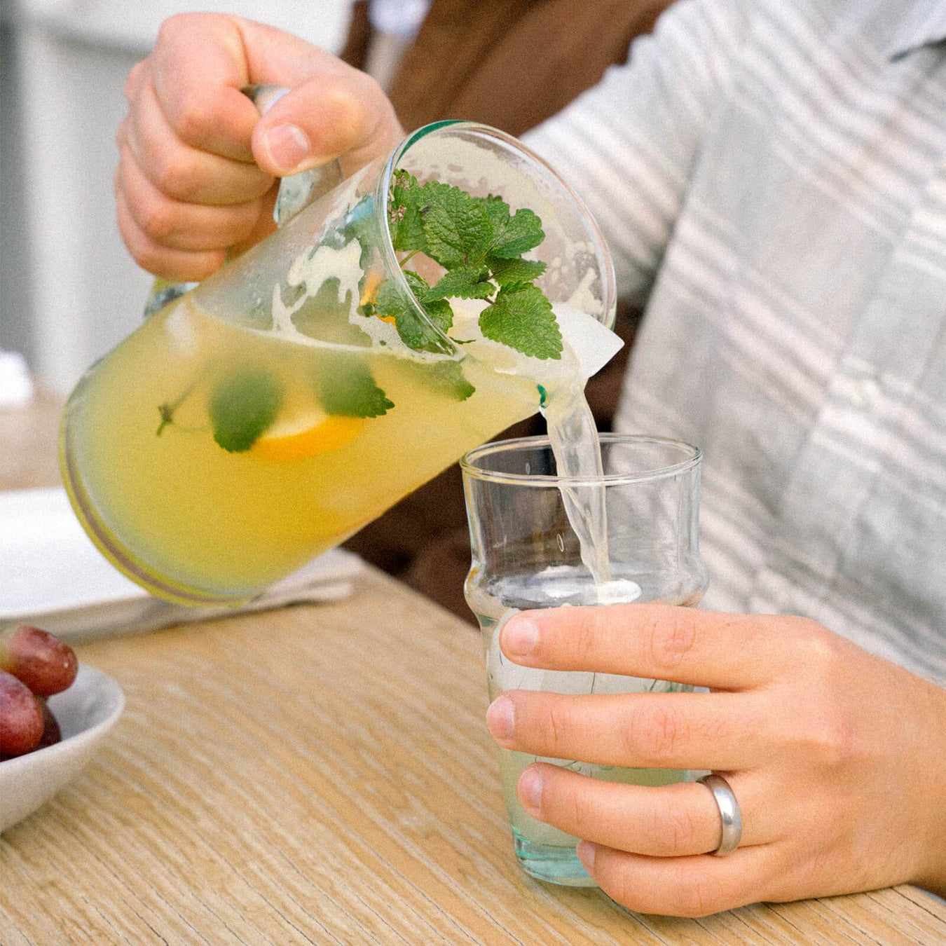 Man pouring a cocktail from a recycled glass handled pitcher 
