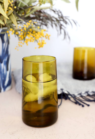 Amber colored recycled Moroccan drinking glasses, styled on a dining table 