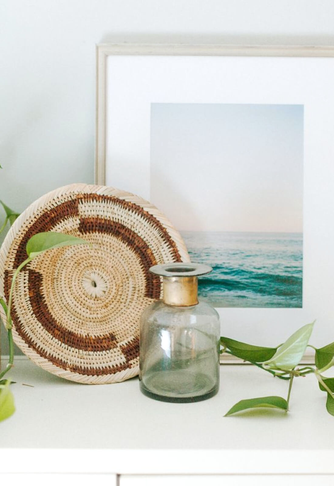 Zambian Plateau basket styled on a shelf with a photo and plant 