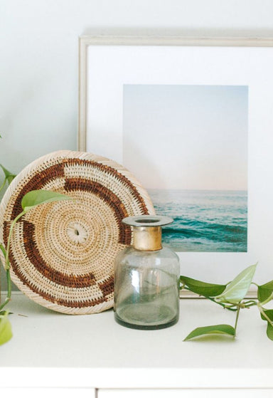 Zambian Plateau basket styled on a shelf with a photo and plant 